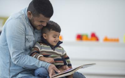 Man with child on lap reading book