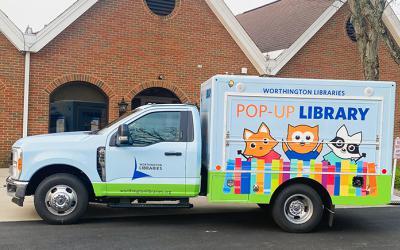 Light blue truck with images of cartoon library mascots along the side