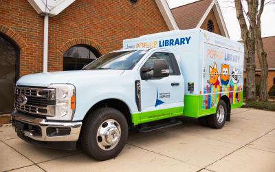 Light blue truck with images of cartoon library mascots along the side
