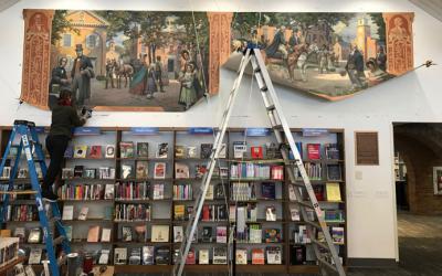 Person on a ladder next to a partially rolled-up canvas
