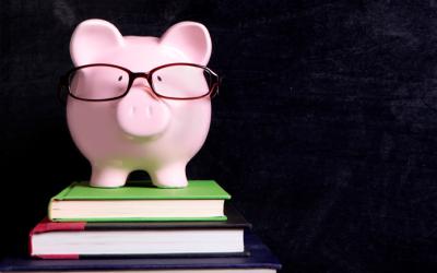 Piggy bank wearing glasses on a stack of books