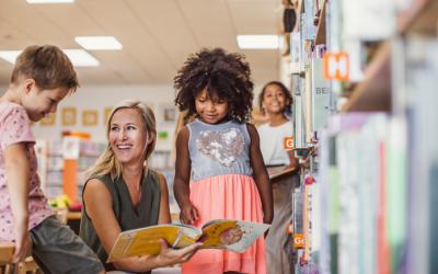 Woman holds book open for children