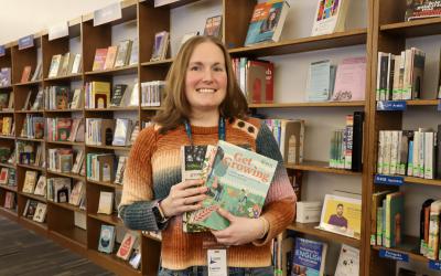 Lauren Robinson standing in front of library bookshelves holding gardening books