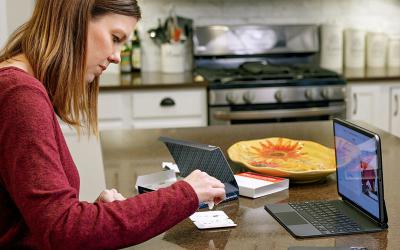 Woman using take-home COVID-19 test with laptop