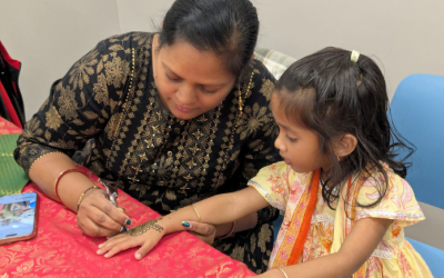 A child receiving a henna tattoo on their hand.