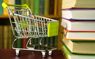 Tiny shopping cart next to a stack of books