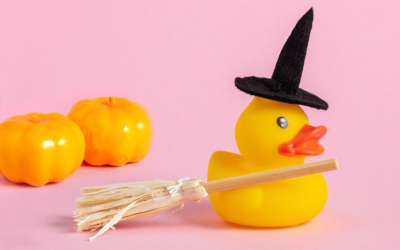 A rubber duck decorated with a small witch's hat and broom.