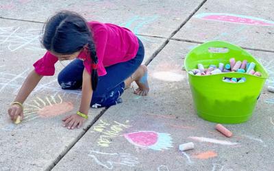 Child drawing with chalk outdoors