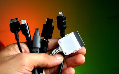Man's hand holding a variety of charging cables