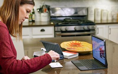 Woman taking COVID test in kitchen with laptop in front of her