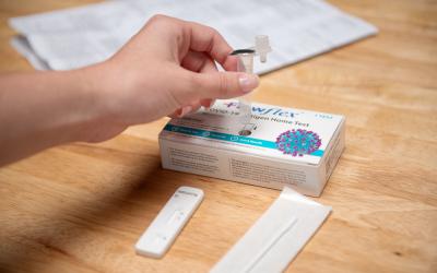 Hand placing vial in Flowflex COVID test box 