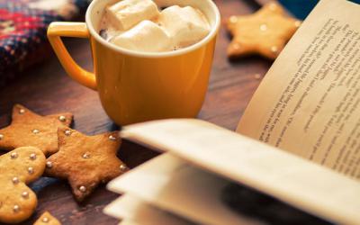 Cookies and mug of hot chocolate near an open book