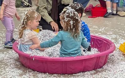 Children playing in plastic pool filled with shredded paper