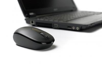 Mouse with scroll wheel in front of laptop