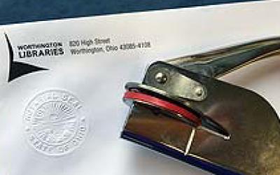 Notary embosser next to a Worthington Libraries logo