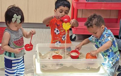 Children playing with objects in a bin of sand