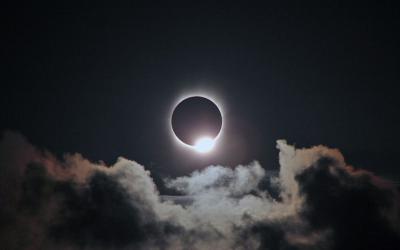 Total solar eclipse in dark sky with clouds