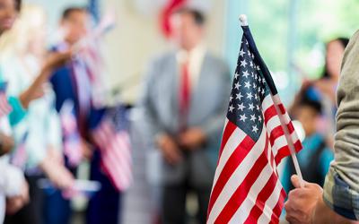 People gathered with someone holding an American flag