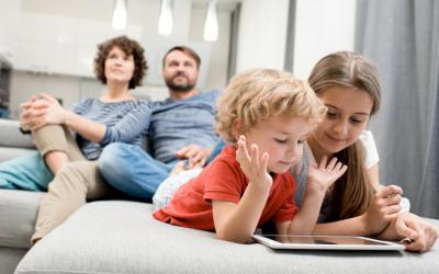 Family in living room, with kids on tablet and parents on the couch