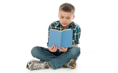 Boy sitting cross-legged reading a book