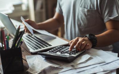 Man sitting a desk with laptop, papers and calculator