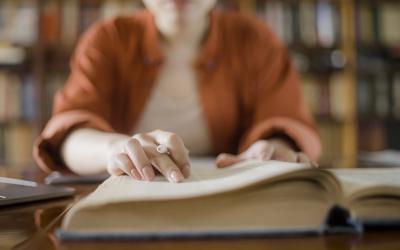 Large book with woman's finger referring to text on page