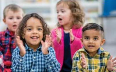 Group of small children sitting and clapping their hands