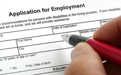 Hand holding pen over form titled Application for Employment